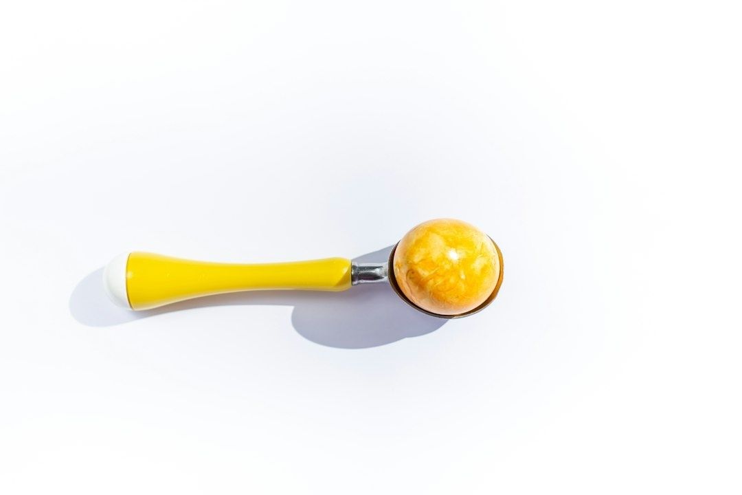 Gul klubba med orange boll på vit yta